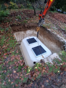 Septic tank lowered into excavated ground pit